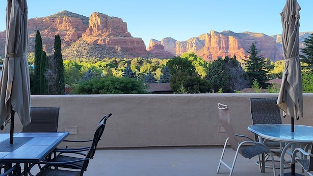 An outdoor patio with a table and chairs, a glass-top table, and two umbrellas. - BEST VIEWS! Sleeps 8 Balcony, Firepit, Lawn, Patio, Wildlife (Sedona)