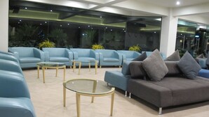 A modern waiting area with blue sofas and glass tables, large windows, and indoor plants. - Suvarnabhumi Oriental Resort (Bangkok)