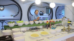 A buffet setup with various food items and a staff member. - Suvarnabhumi Oriental Resort (Bangkok)