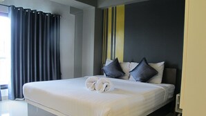 A modern hotel room with a large bed, dark curtains, and a striped wall. - Suvarnabhumi Oriental Resort (Bangkok)