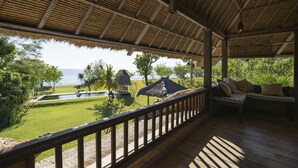Ein überdachter Außenbereich mit Holzterrasse, Pool und Meerblick.