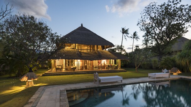 Ein Haus mit Pool, einer überdachten Terrasse und einem Rasen.