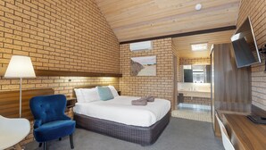 Una habitación con una cama, una silla azul, un escritorio y un espejo.