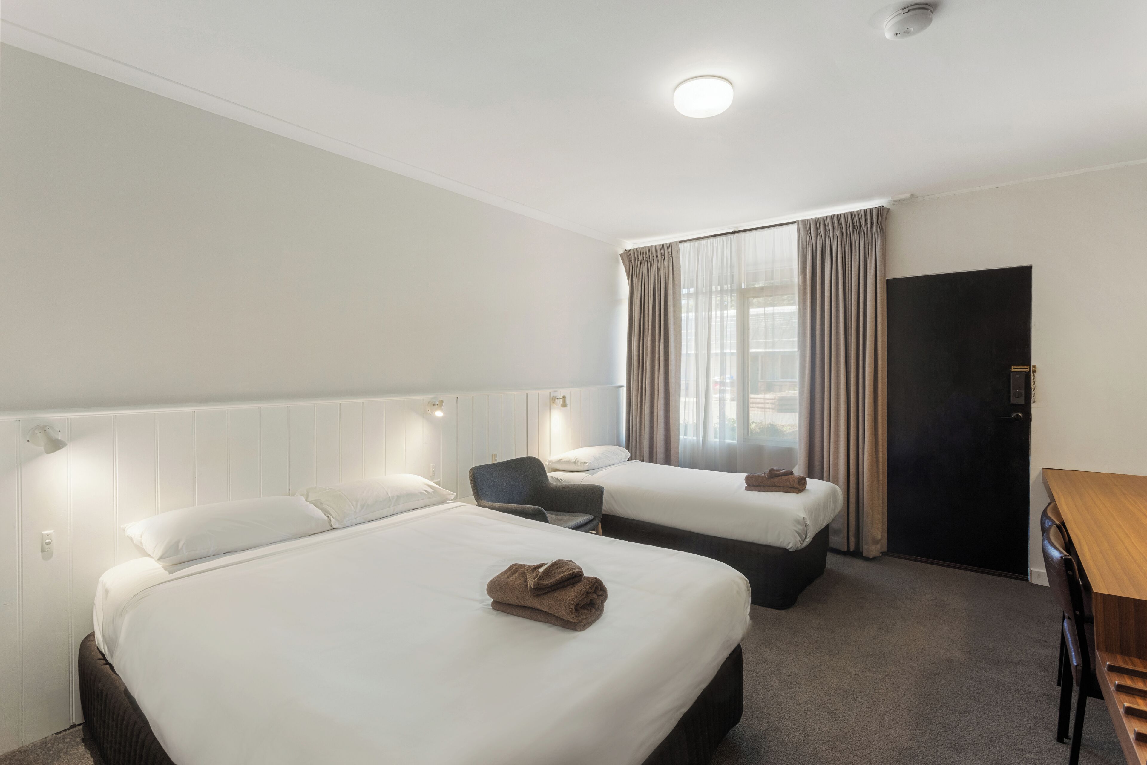 Een hotelkamer met twee bedden, een bureau en een stoel.