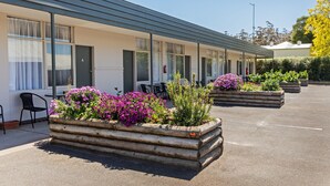 Un motel con una fila de habitaciones, asientos exteriores y jardineras con flores.