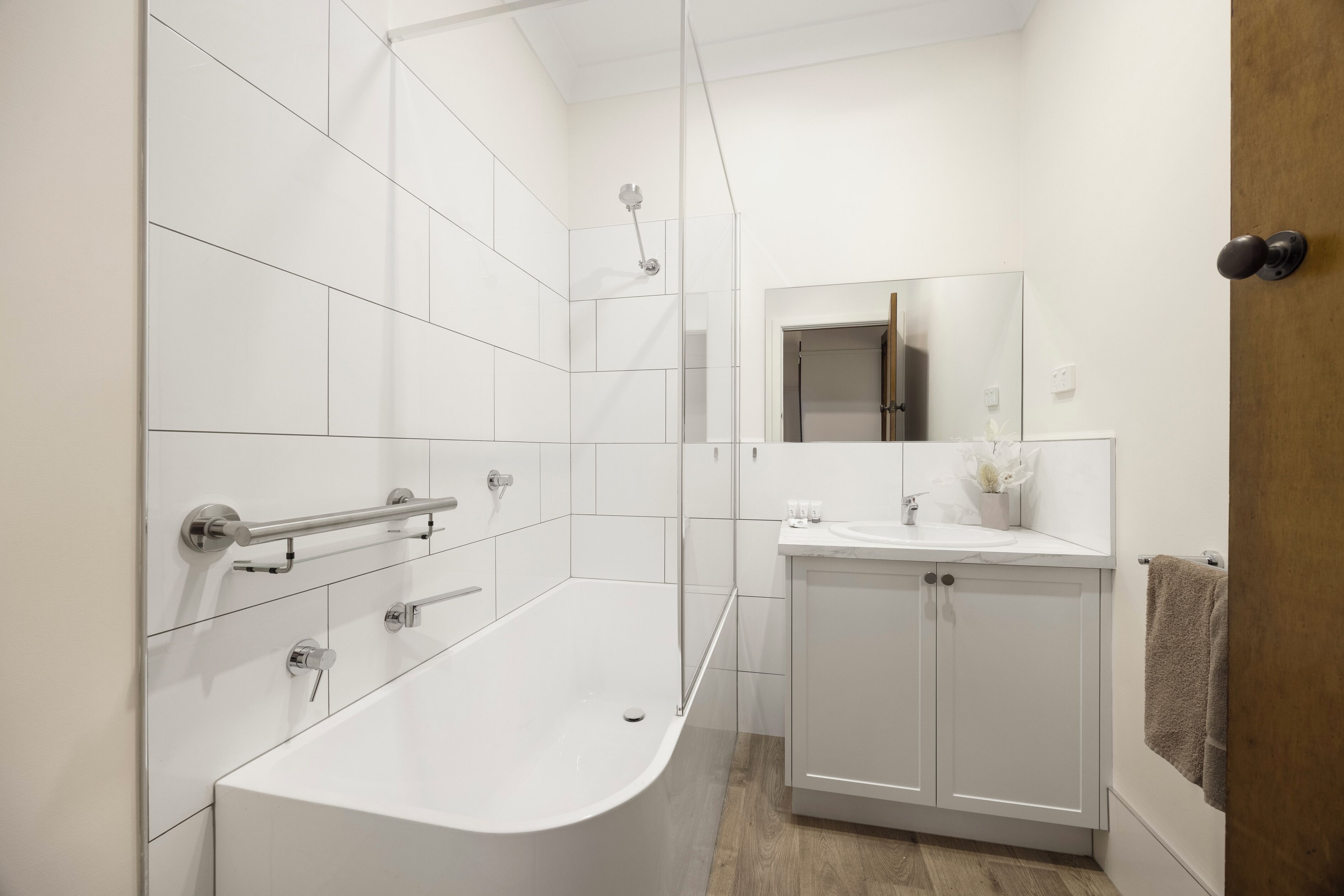 Un baño moderno con una bañera independiente, un tocador con espejo y un perchero para toallas.