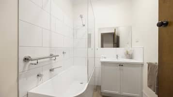 Un baño moderno con una bañera independiente, un tocador con espejo y un perchero para toallas.