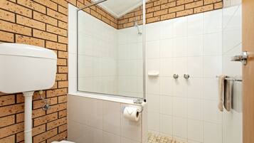 Un baño con inodoro, lavamanos, ducha y espejo.