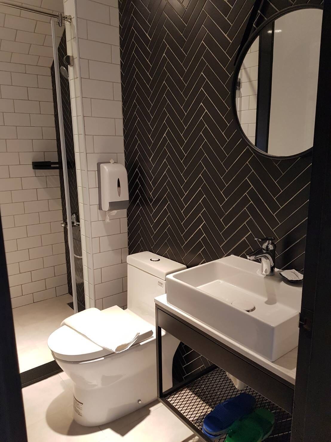 A modern bathroom with a white toilet, a sink with a mirror, and a shower area.