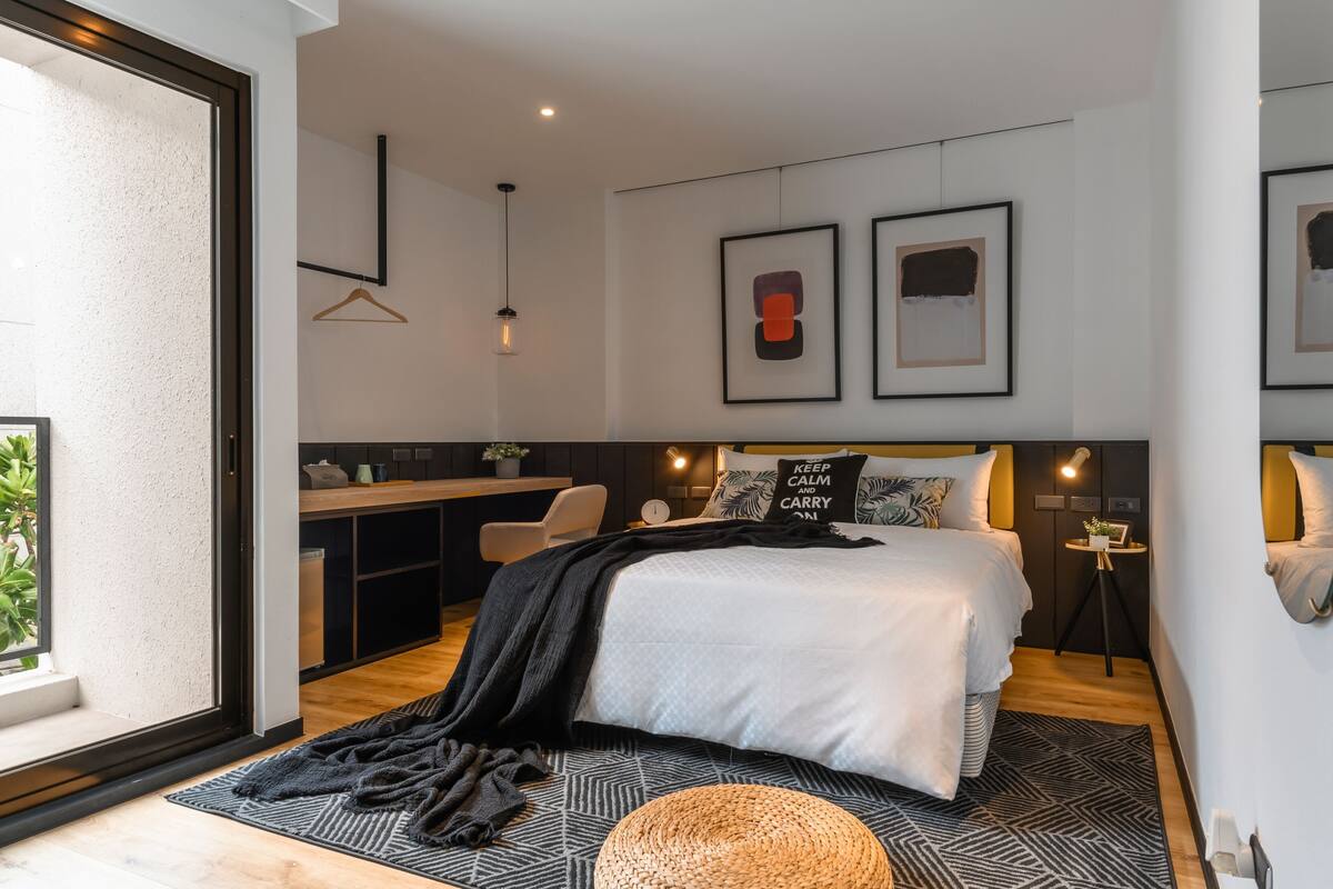 Een moderne slaapkamer met een groot bed, nachtkastjes, een bureau en een hanglamp.