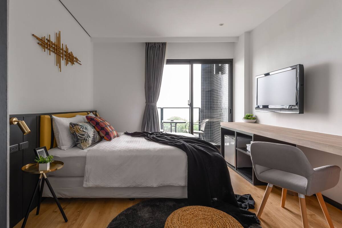 Een moderne slaapkamer met een bed, nachtkastje, stoel en een televisie.