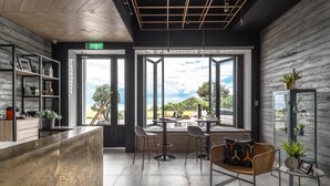 A modern interior with a reception desk, seating area, and large windows offering a view of the outdoors. - Hido Hotel I (Hengchun)