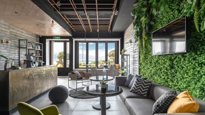 A modern interior with a reception desk, seating area, and a large window offering a view of the outdoors. - Hido Hotel I (Hengchun)