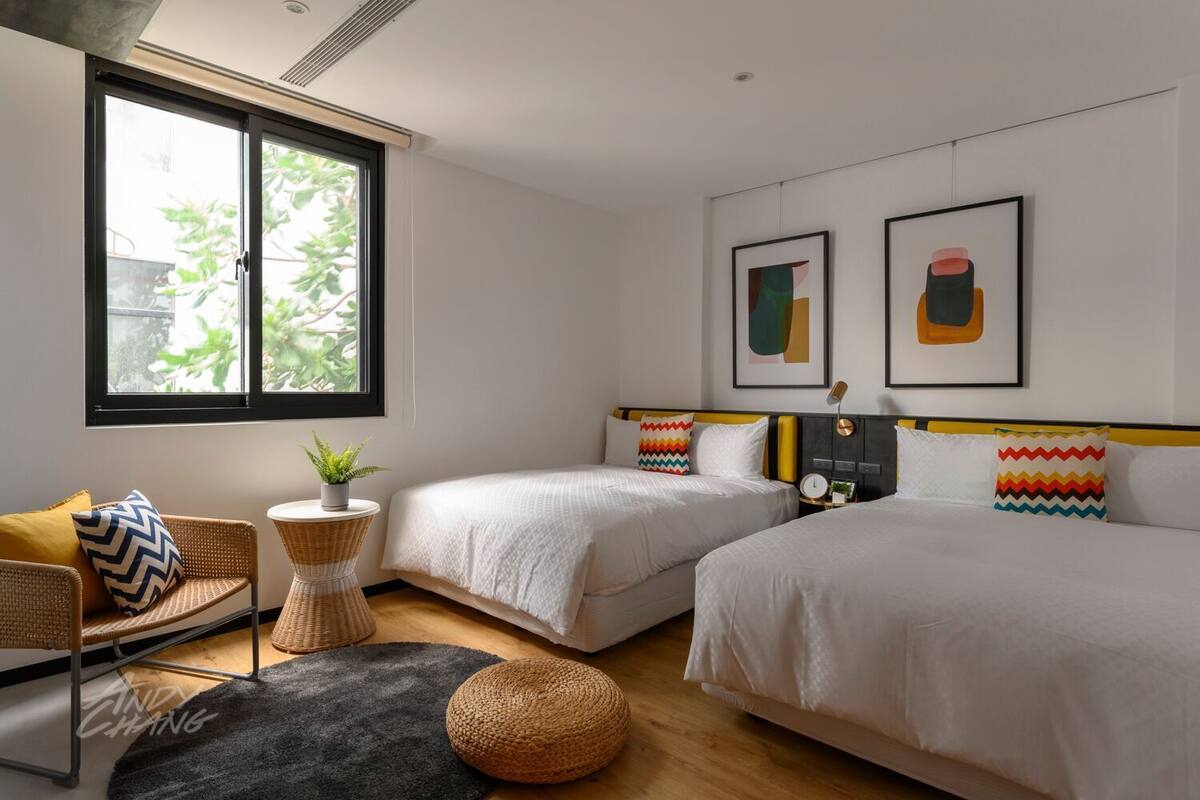 Een moderne slaapkamer met twee bedden, een zithoekje en kunstwerken aan de muur.
