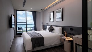 A modern hotel room with a large bed, a bedside table, a TV, and a view of the sea. - Hido Hotel II (Hengchun)