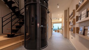 A modern interior with a revolving door, a staircase, and a hallway leading to a bright area with a view. - Hido Hotel II (Hengchun)