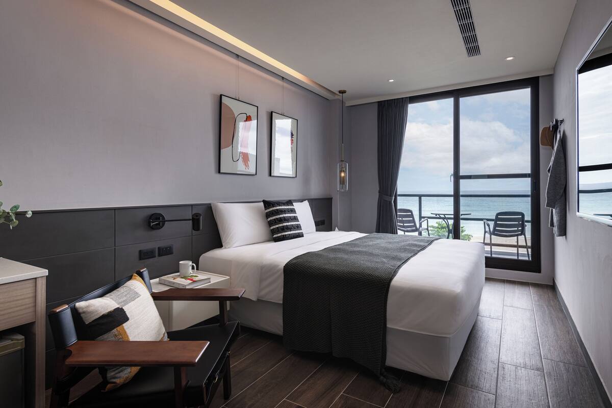 Una habitación de hotel moderna con una cama grande, un escritorio y vistas al mar.