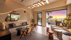 A modern interior with a seating area, a reception desk, and a view of the sunset. - Hido Hotel II (Hengchun)