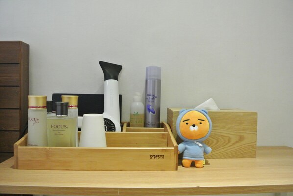 A wooden tray with various personal care products and a plush toy on a wooden surface. - Shire Hotel (Busan)