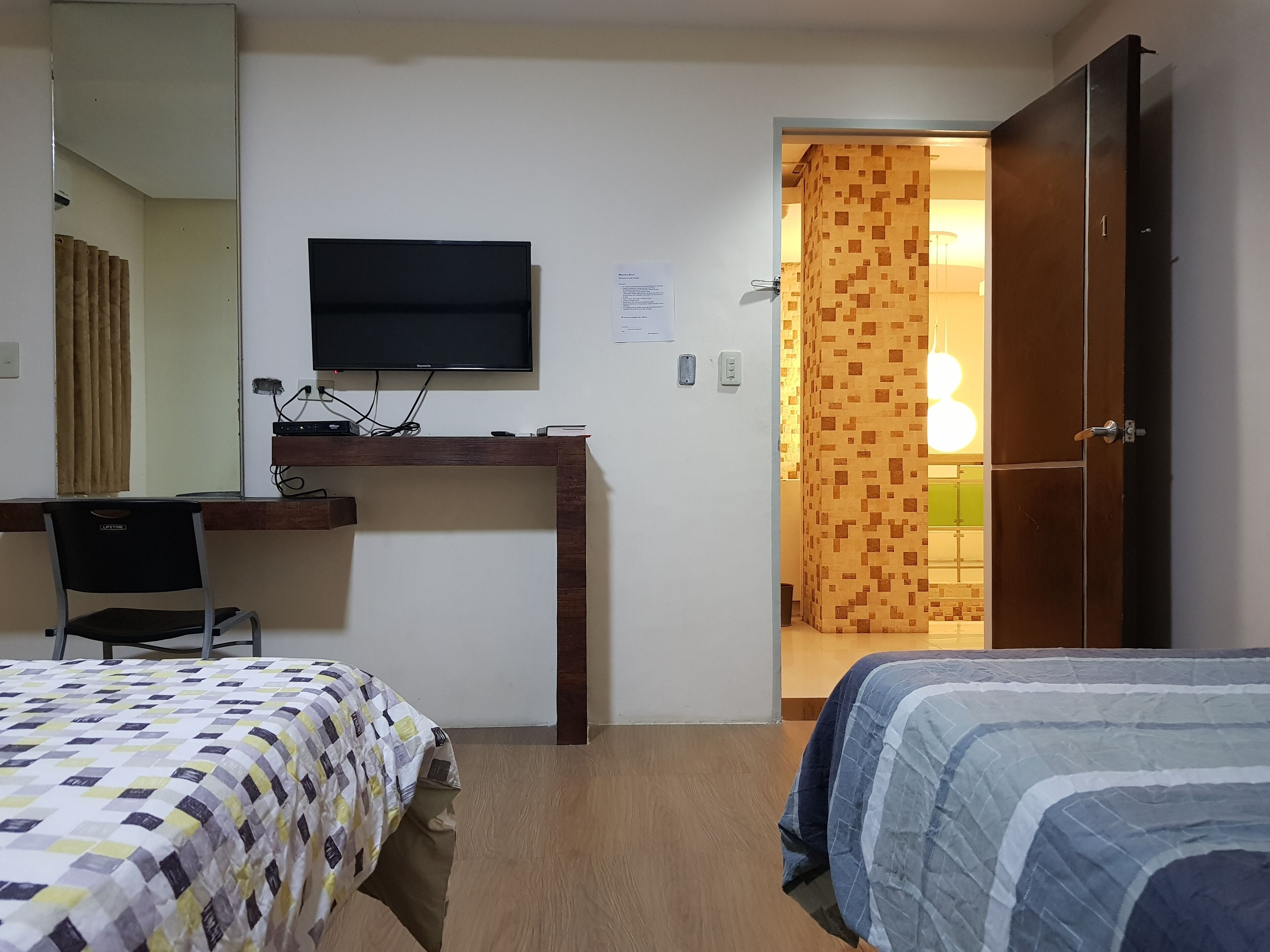 A hotel room with a bed, a desk with a computer, a TV, and a wardrobe.