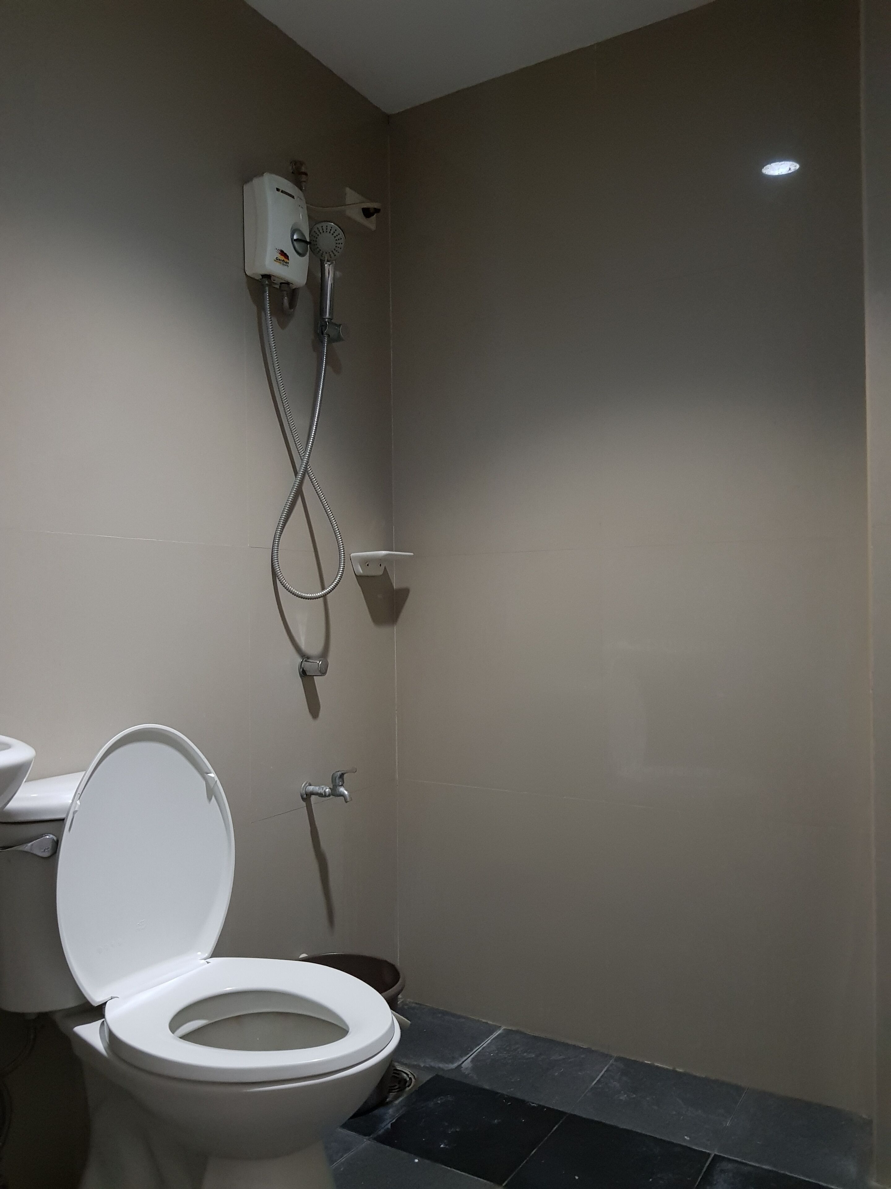 Un baño con inodoro, ducha y un calentador mural.