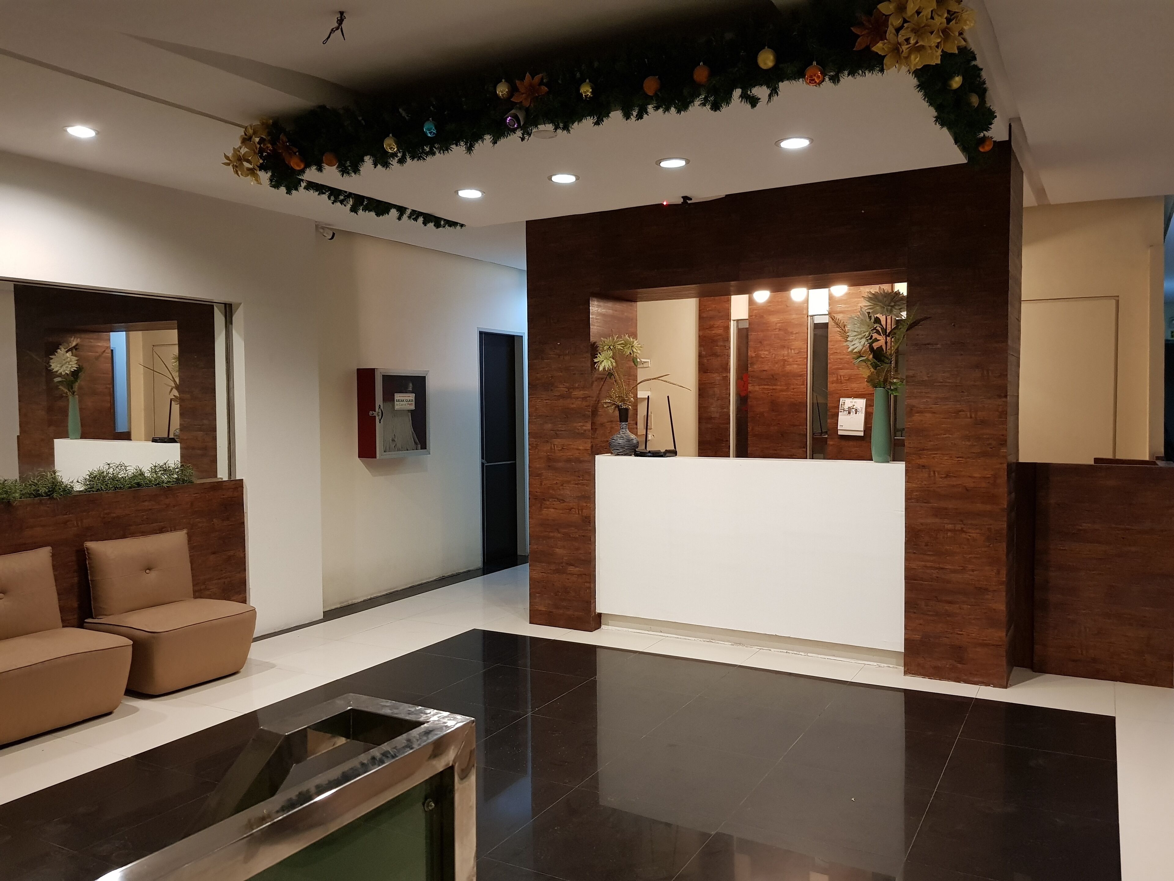Un área de recepción moderna con un mostrador de madera, un sofá y una mesa de centro de vidrio.