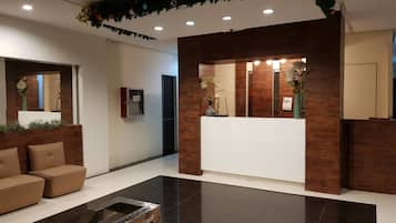 Un área de recepción moderna con un mostrador de madera, un sofá y una mesa de centro de vidrio.