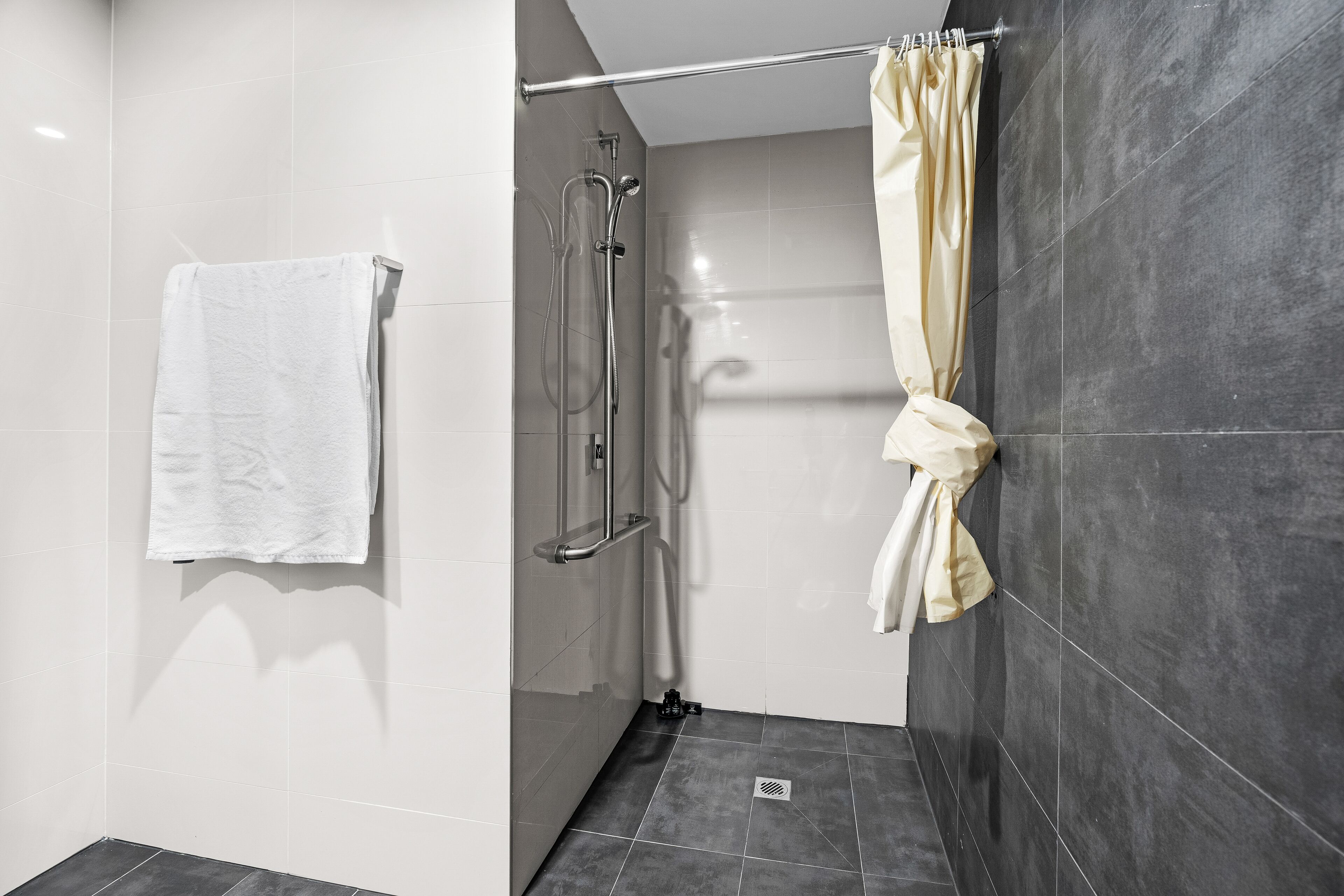 Une salle de bain moderne équipée d’une douche, d’un porte-serviettes et d’un rideau.