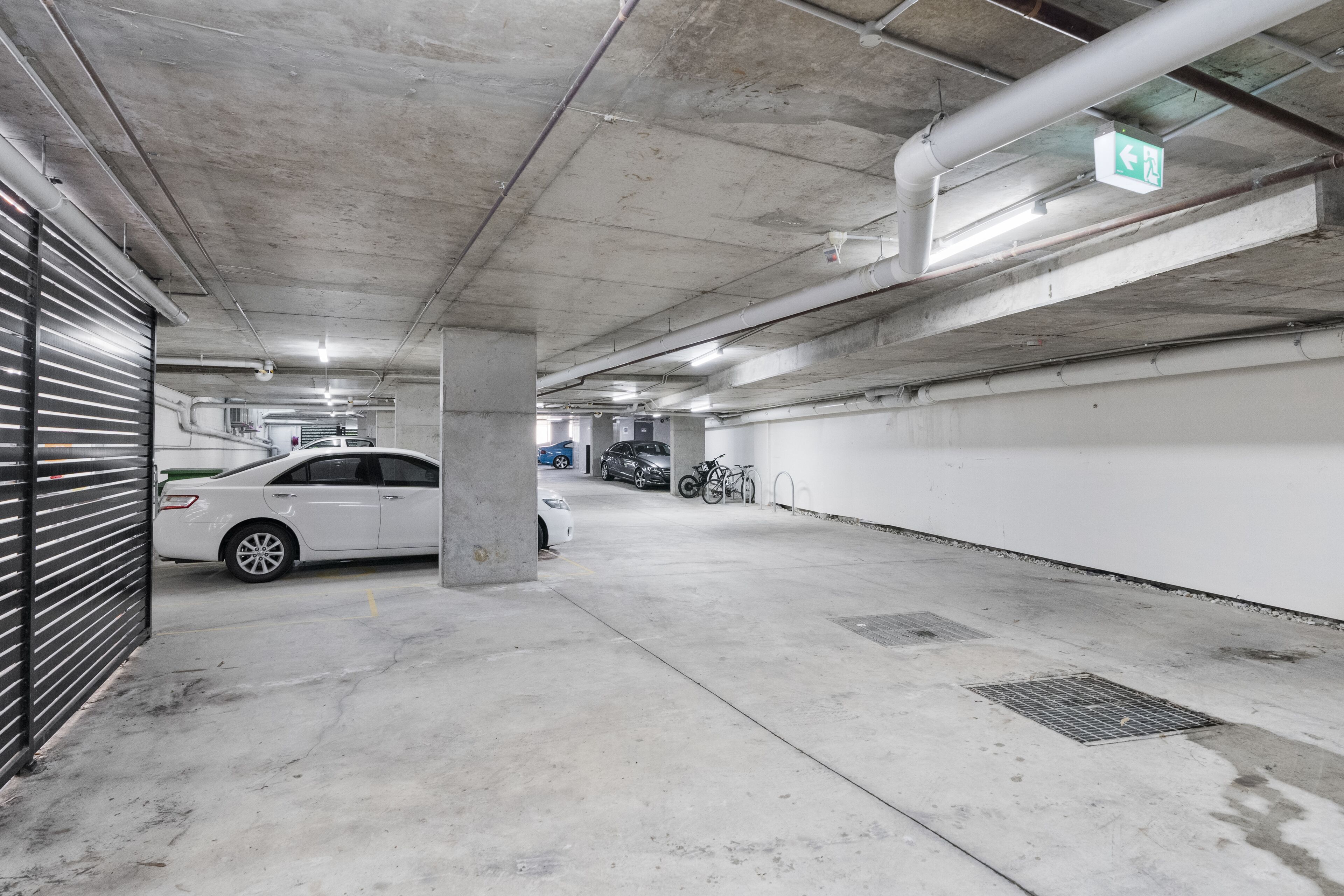 Eine mehrgeschossige Parkgarage mit Betonpfeilern, einem weißen Auto und einem Fahrrad.