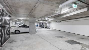 Eine mehrgeschossige Parkgarage mit Betonpfeilern, einem weißen Auto und einem Fahrrad.