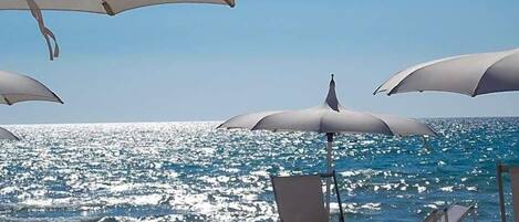 Playa privada, playa de arena blanca, camastros y sombrillas