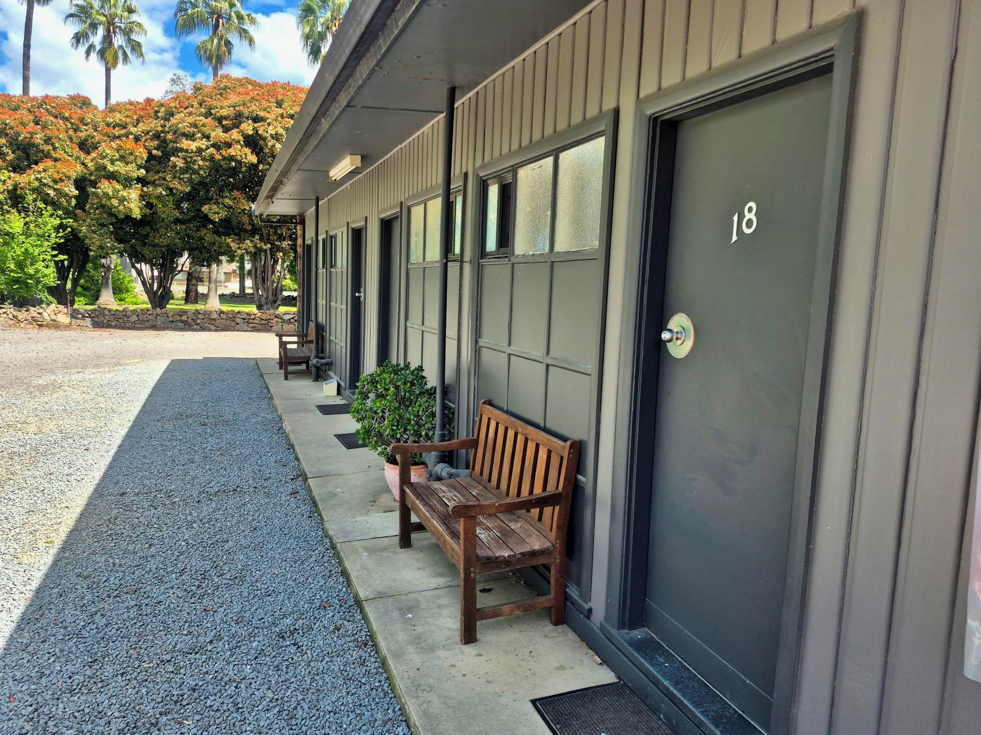 A building with a number 18 door, a bench, and a small potted plant.