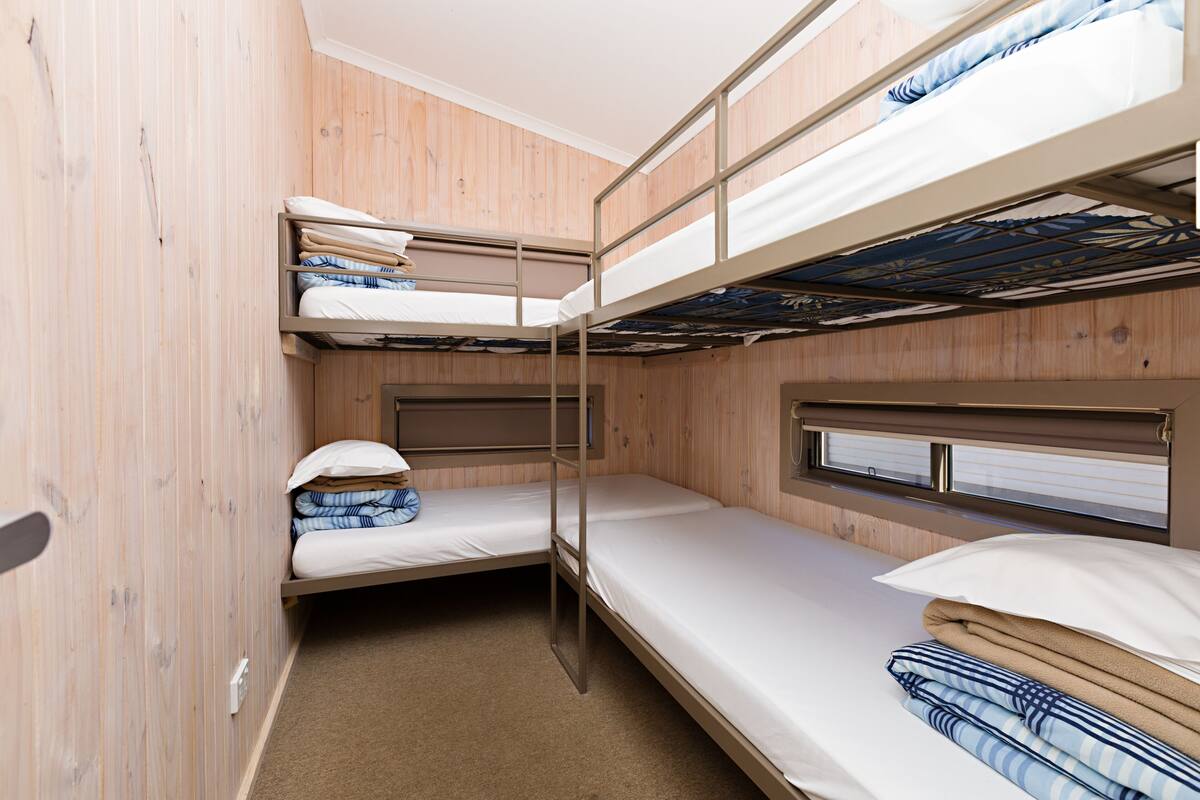 A bunk bed room with wooden walls and a window.