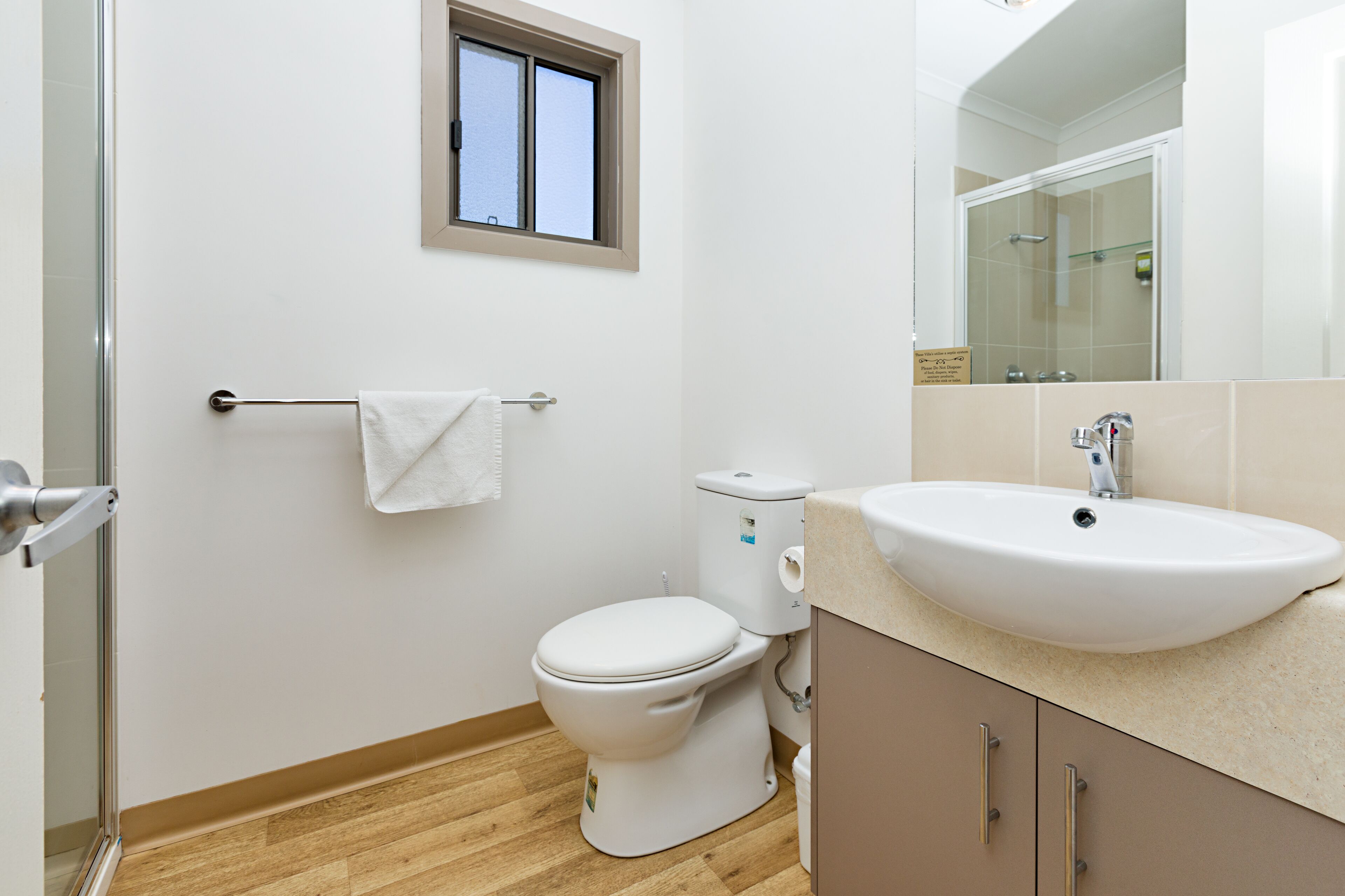 A bathroom with a toilet, sink, and a window.