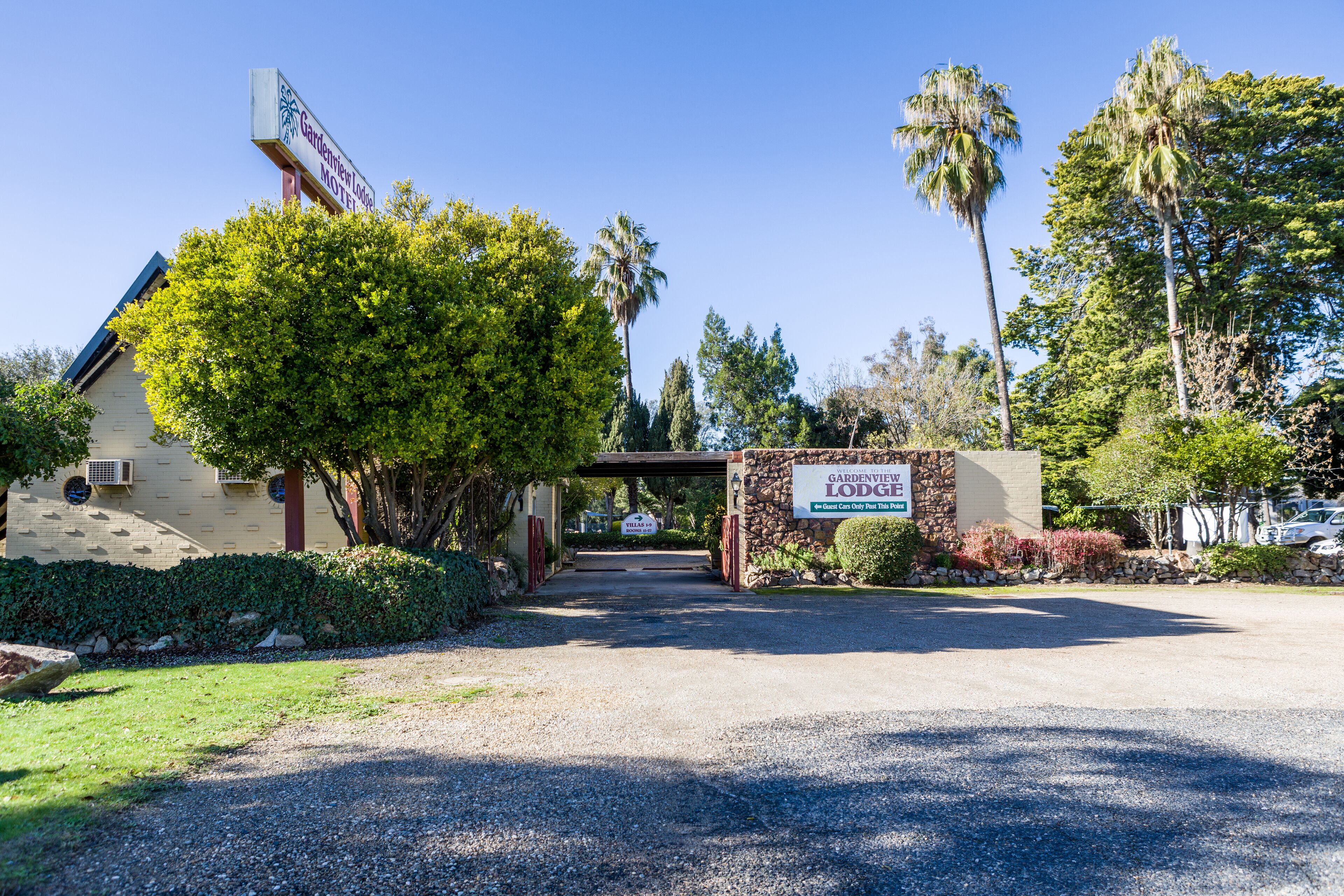 The entrance to the Gardenview Lodge Motel with a clear driveway and surrounding greenery.