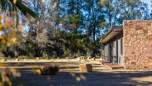 A stone building with a porch and outdoor seating area, surrounded by trees and rocks.