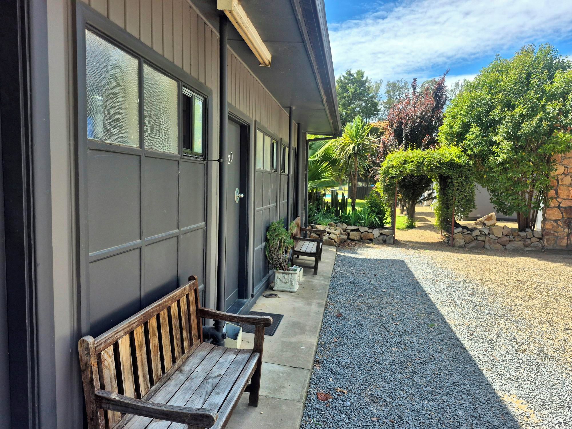 A building with a covered outdoor seating area, a gravel path, and a stone wall.
