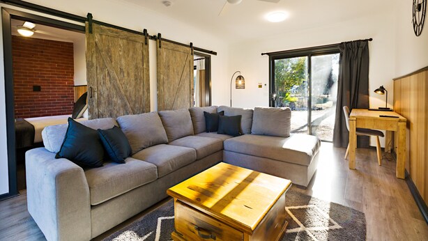 A modern living room with a sectional sofa, a wooden coffee table, and a sliding barn door.