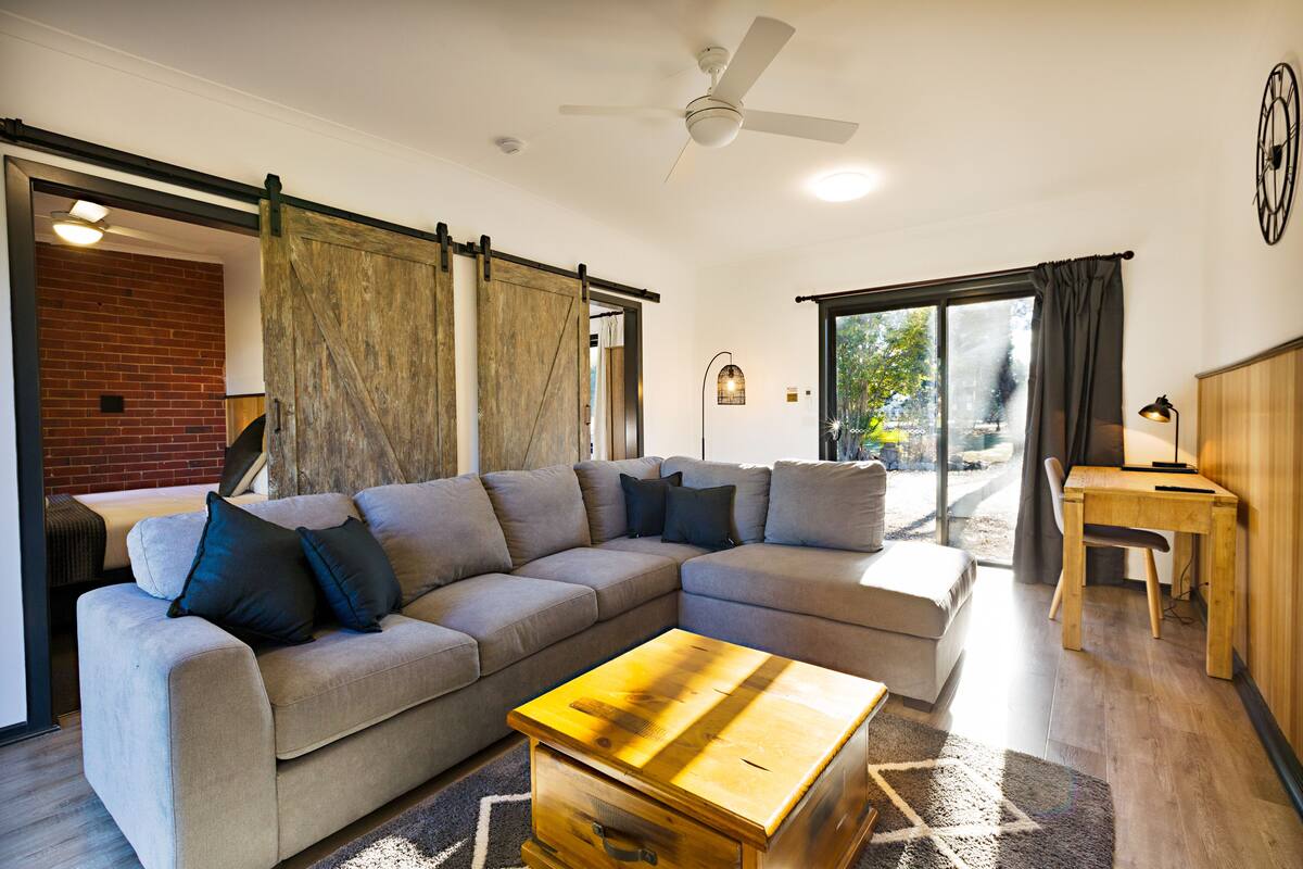 A modern living room with a sectional sofa, a wooden coffee table, and a sliding barn door.