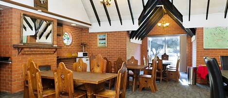 A restaurant with brick walls, wooden tables and chairs, and a high ceiling with exposed beams.