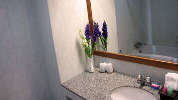 Un baño con encimera de granito, un lavabo blanco, un espejo y una bañera.