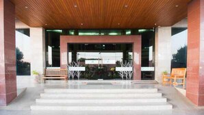 A building entrance with a wooden ceiling, steps leading up to a covered area, and a bench outside. - JP Emerald Hotel (Yasothon)