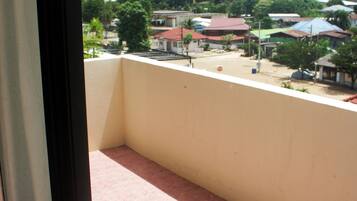 Un balcón con vistas a un barrio residencial, que incluye casas y una calle.