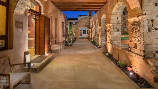 Un pasillo con arcos de piedra, vigas de madera y plantas en macetas.