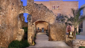 Un antiguo arco de piedra que da paso a un edificio moderno con un letrero del Monastery Boutique Hotel.