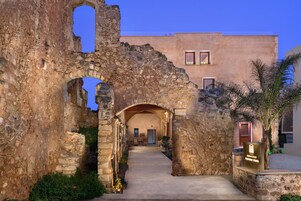 Un arc en pierre datant de l’Antiquité mène à un bâtiment moderne sur lequel on peut lire l’enseigne du « Monastery Boutique Hotel ».