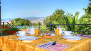 Mesa posta para o café da manhã com vista para uma paisagem montanhosa.