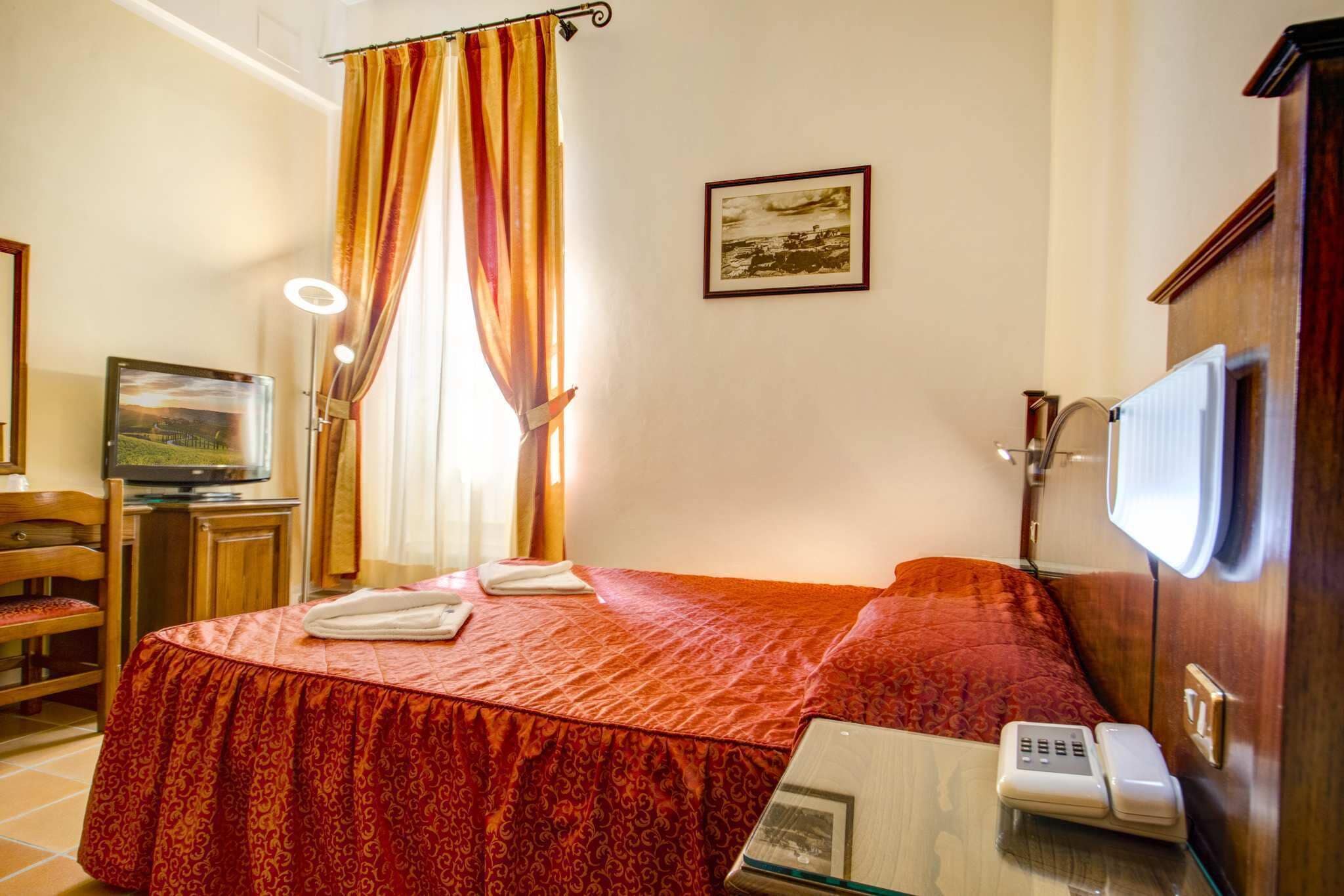 Une chambre d’hôtel avec un lit, une télévision, un téléphone et un tableau au mur.