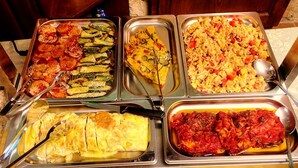 A buffet with various dishes including pasta, vegetables, and a meat dish.