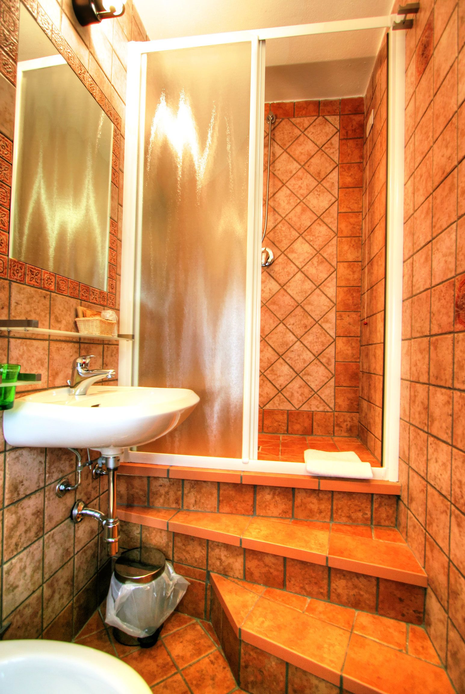 Ein Badezimmer mit Waschbecken, Spiegel, Dusche und gefliesten Wänden.